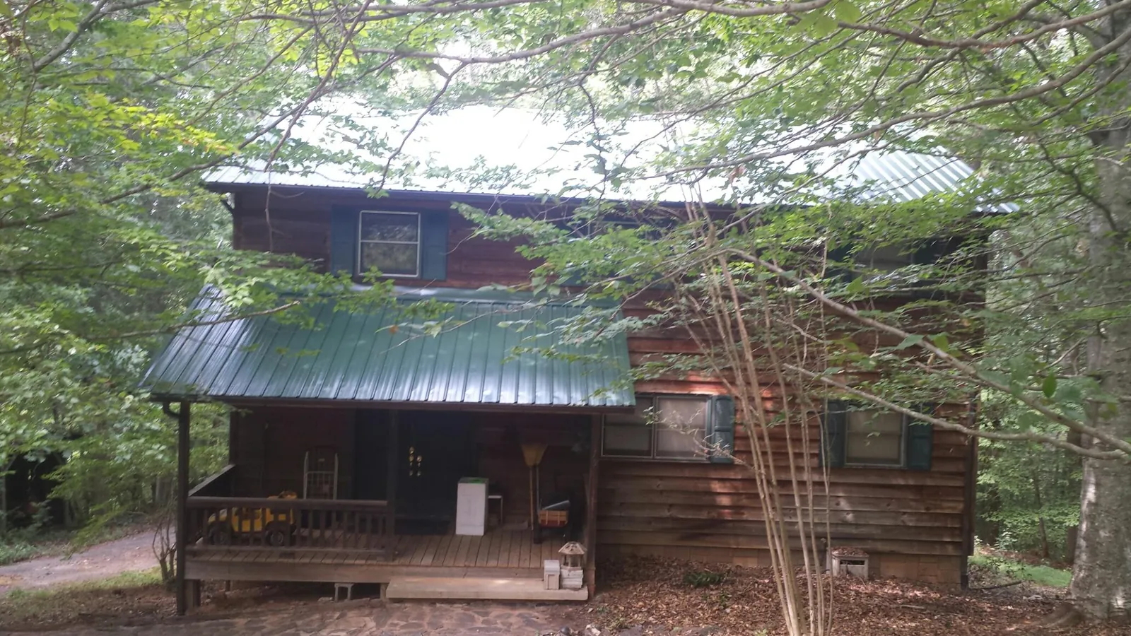 Green metal roof and covered porch on a log cabin in Hackensack