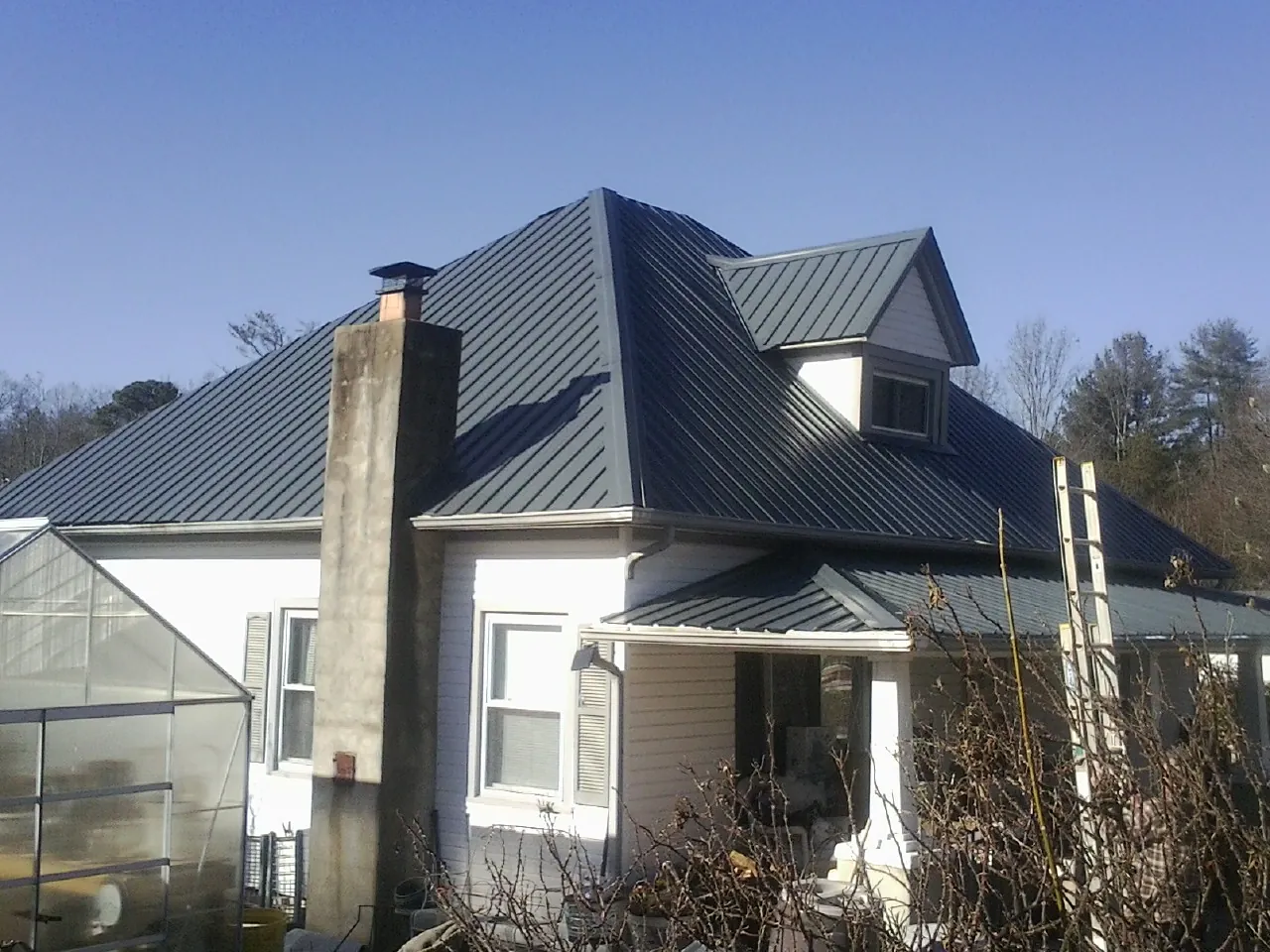 Dark blue standing seam metal roof on a white farmhouse with dormer — Slate & Tile Roof Repair by Roofing Brothers in Hackensack
