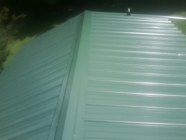 New green metal panels meeting at the ridge of a roof — Flat Roof Repair work by our crew in Hackensack