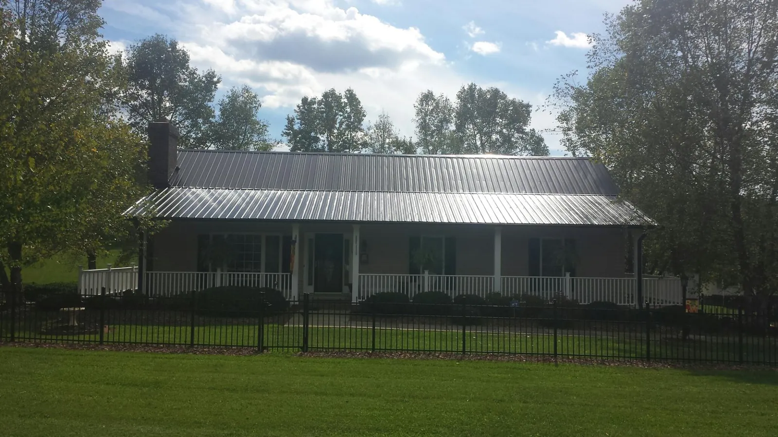 Gray metal roof on a brick ranch with a full width front porch — Gutter Guard Installation work by our crew in Hackensack