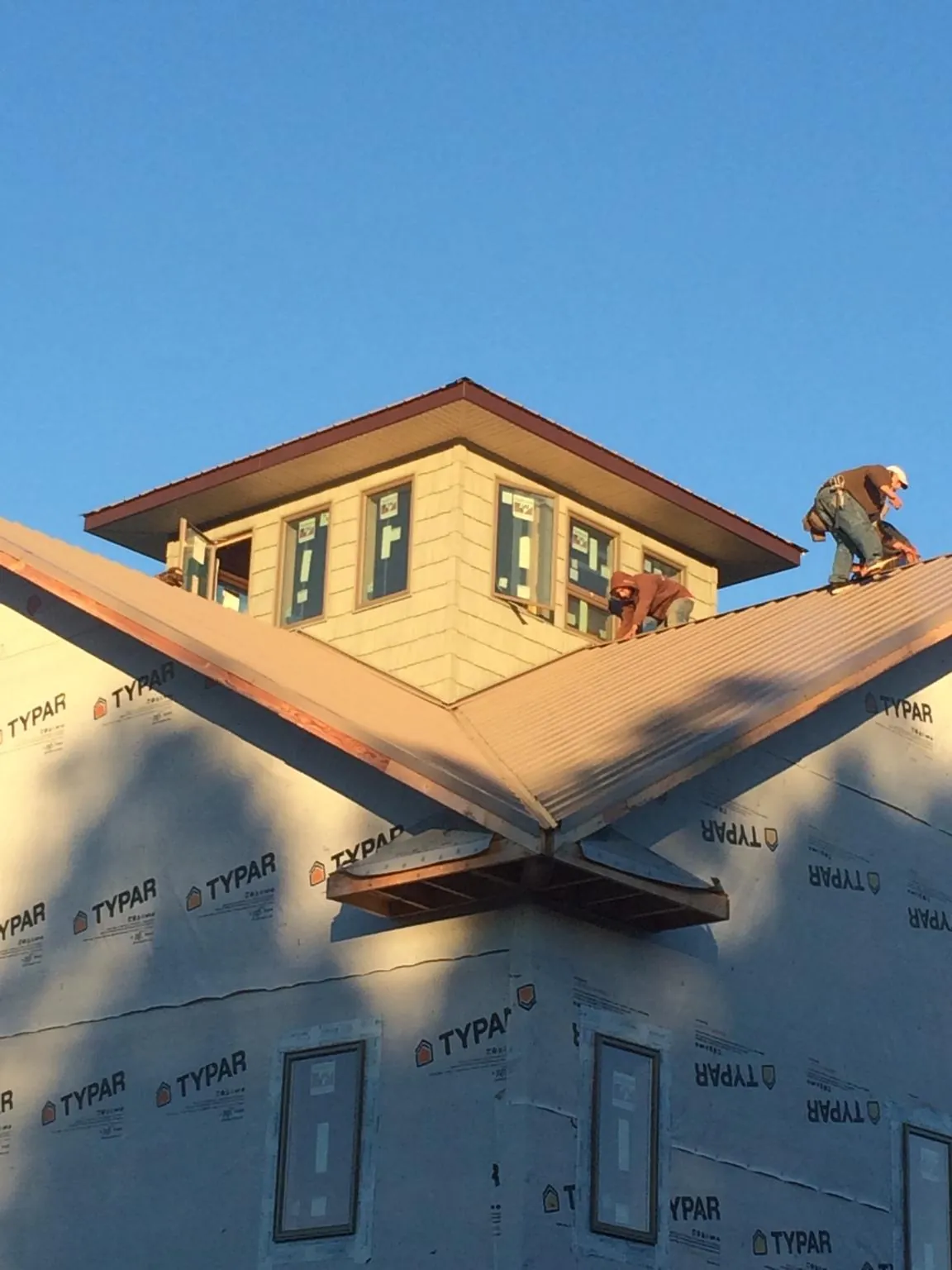 Roofers working around a rooftop cupola on a new metal roof at sunset — Roof Waterproofing in Hackensack by Roofing Brothers
